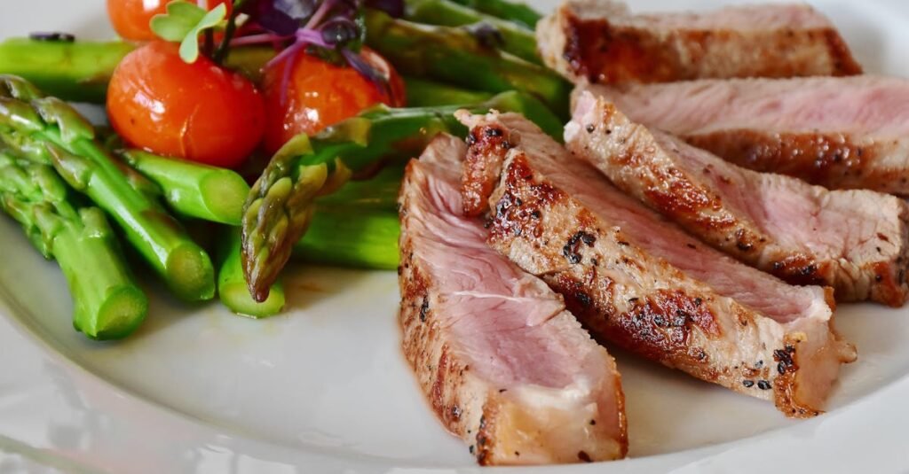 Close-up of grilled steak slices with asparagus and cherry tomatoes, perfect for a healthy meal.