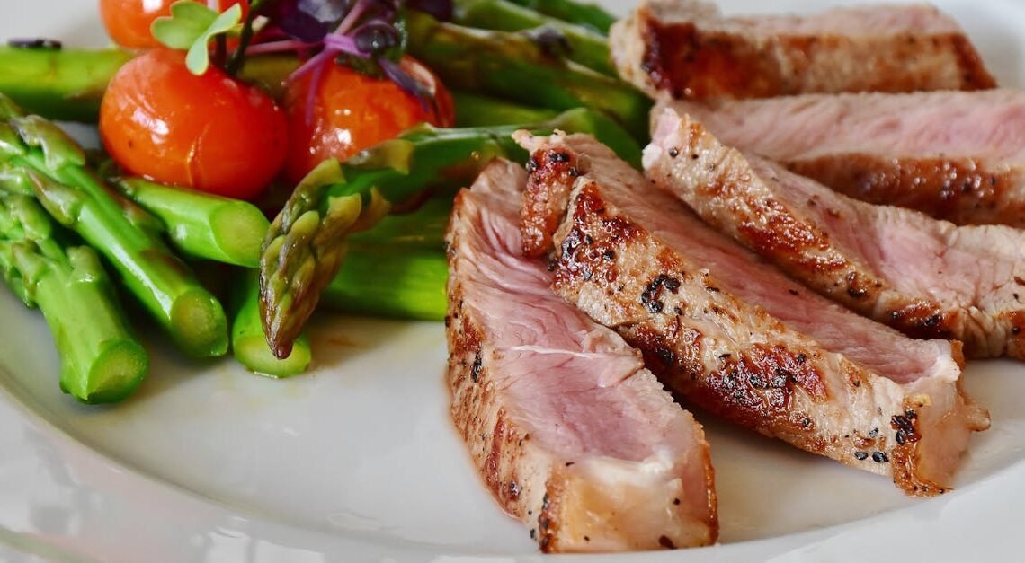 Close-up of grilled steak slices with asparagus and cherry tomatoes, perfect for a healthy meal.